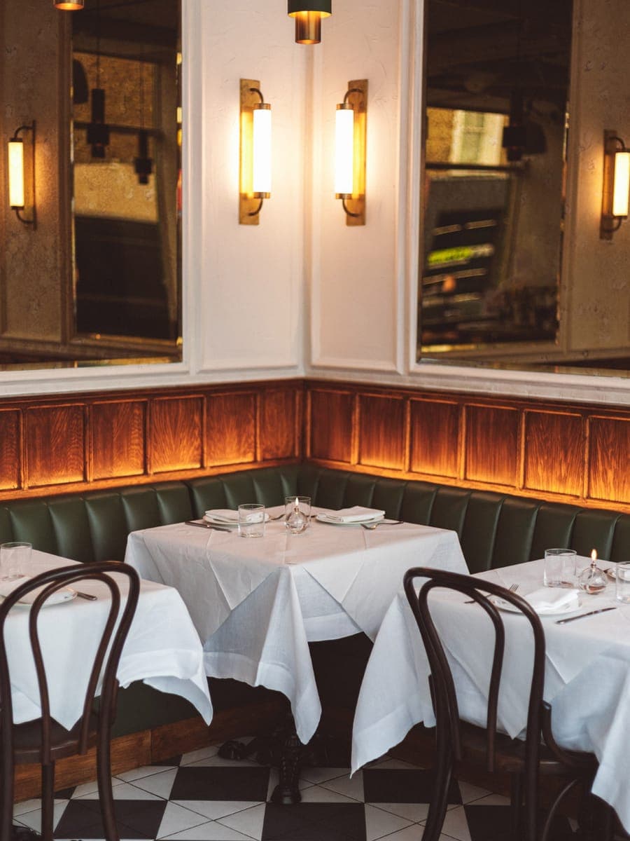 Dorian's dining room in Notting Hill — green banquette, white linen and a chequerboard floor